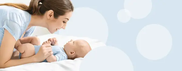 Mama patrzy z miłością na swoje dziecko, które właśnie zaczyna gaworzyć, wydając pierwsze dźwięki radości.