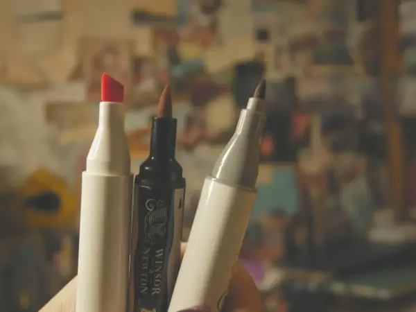 Trzy markery, jeden z czerwoną końcówką, jeden czarny Winsor & Newton i jeden szary, gotowe do tworzenia dzieł sztuki.