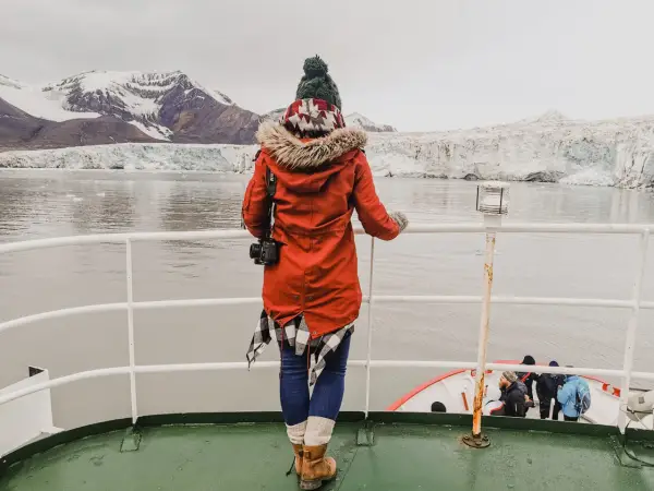 Podróżniczka podziwia lodowce na archipelagu Svalbard. W oddali widać góry i morze.