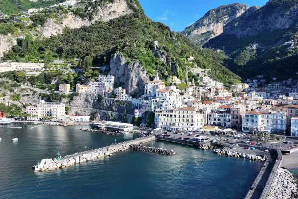 La **conca dei Marini** si apre sul mare blu, con case colorate aggrappate alla scogliera verdeggiante.
