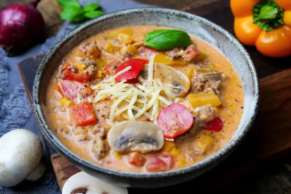 Herzhaftes pizzasuppe rezept mit Hackfleisch, Paprika, Mais und Pilzen, garniert mit Käse und Basilikum.