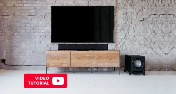 Un salon moderne avec une TV, une barre de son et un **pre out subwoofer** noir sur un meuble en bois.