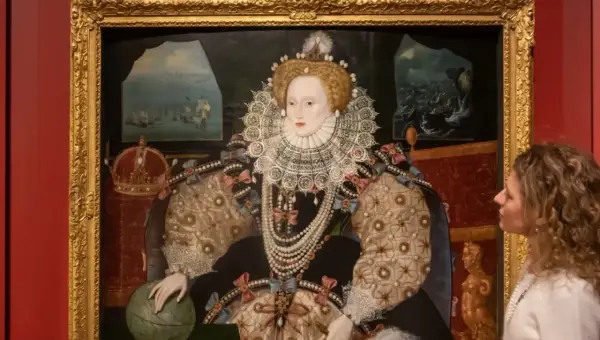 A woman gazes at a regal queen Elizabeth portrait, adorned in a jeweled gown and ruff, with a globe and crown nearby.