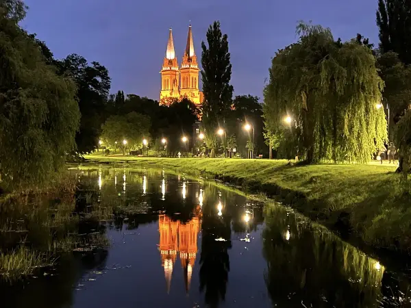 Wieczorny spacer nad rzeką we Włocławku. Podświetlona katedra odbija się w wodzie, tworząc magiczny widok. Idealne włocławek atrakcje na weekend.