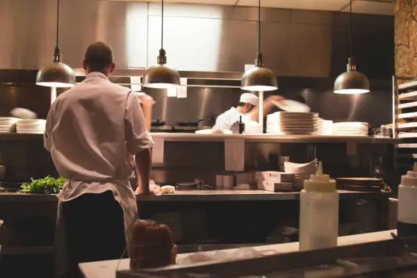 Kucharz w białej koszuli i fartuchu pracuje w kuchni restauracyjnej. To idealne miejsce, by napisać list motywacyjny kucharz.