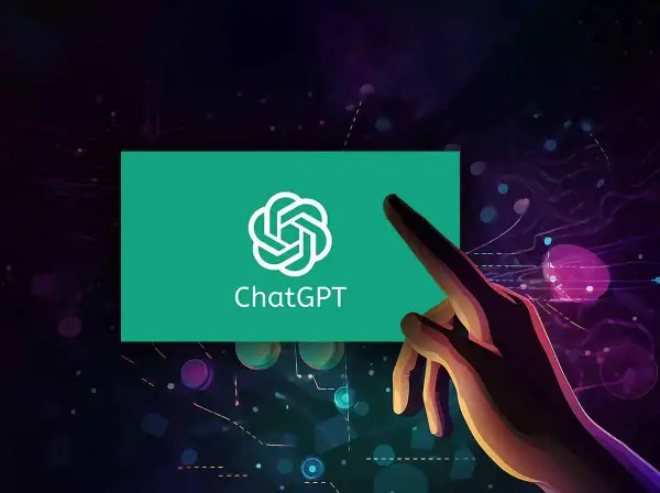 Dłoń dotyka ekranu z logo ChatGPT, symbolizując interakcję z zaawansowaną sztuczną inteligencją GPT.