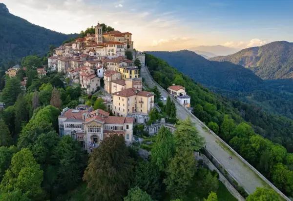 Borgo pittoresco su un colle, ideale per scoprire cose da fare a Varese. Case colorate, un campanile e sentieri panoramici tra il verde.