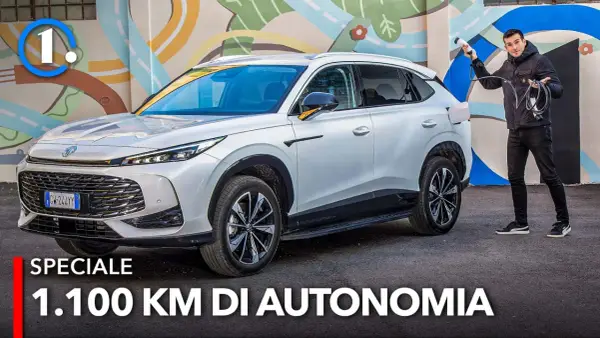 Un uomo con cavo di ricarica accanto a un MG HS Hybrid+ bianco, pronto per un viaggio di 1.100 km.