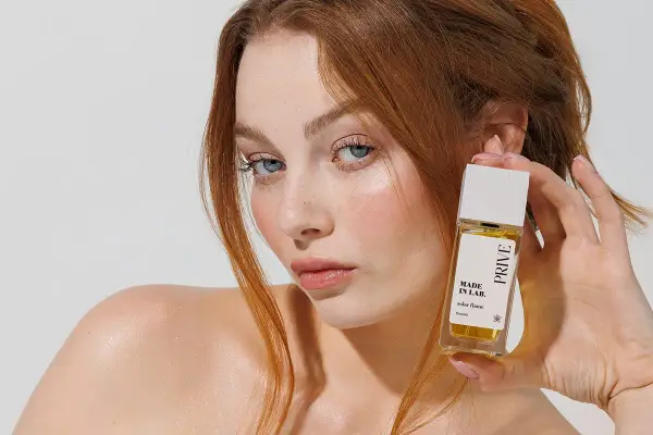 Ruda kobieta z niebieskimi oczami prezentuje perfumy "Made in Lab". Opinie o nich są zachęcające.
