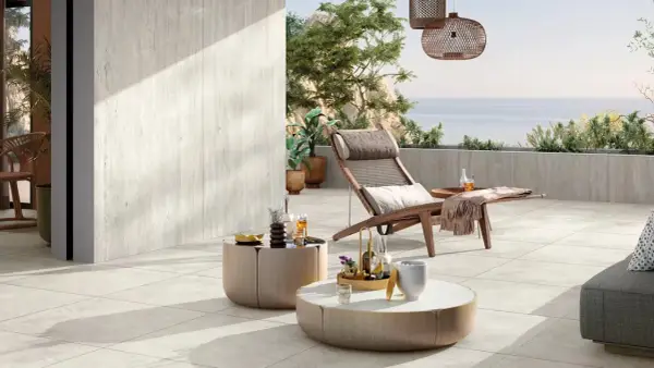 Terrasse en travertin avec mobilier de jardin et vue sur la mer.