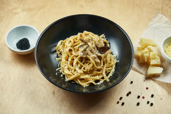 Un piatto di pasta al tartufo, un sapore autentico del cibo perugino, con scaglie di parmigiano e pepe nero.