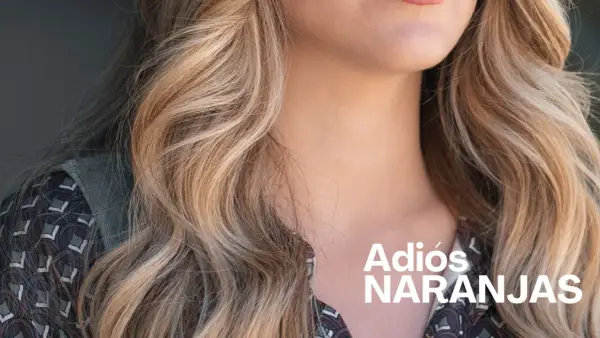 Cabello rubio con mechas matizadas, luciendo un estilo fresco y vibrante. "Adiós Naranjas" en texto blanco.