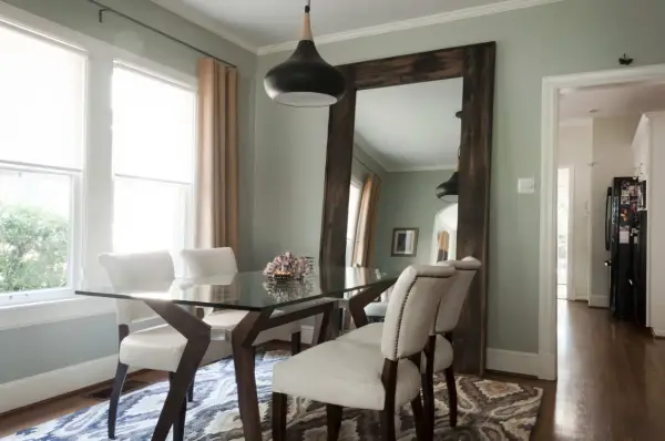 Un grand miroir rustique reflète la salle à manger, offrant une idée de où mettre un miroir dans une salle à manger pour agrandir l'espace.