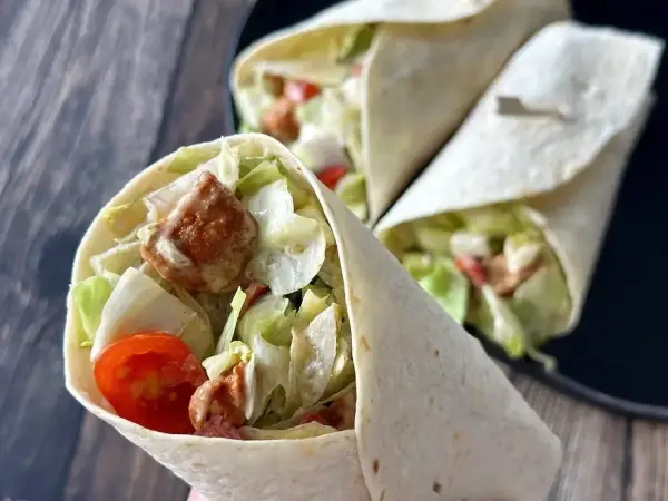 Pyszna tortilla z kurczakiem, chrupiącą sałatą i pomidorkami. Idealna na szybki lunch.
