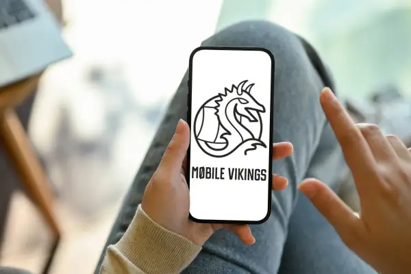Ręka trzyma smartfon z logo Mobile Vikings. To sieć komórkowa dla tych, którzy cenią wolność i niezależność.