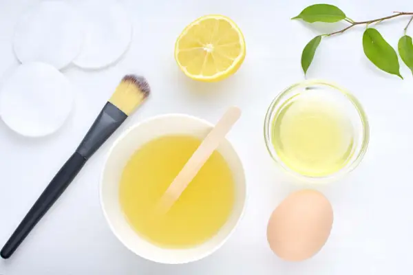 Ingredientes para una mascarilla casera para el pelo: huevo, limón, aceite y aplicador.