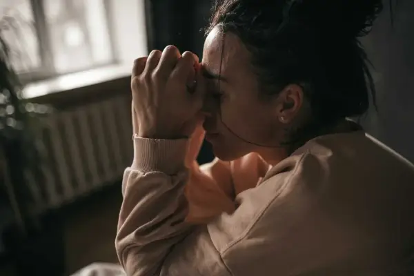 En kvinna med händerna mot pannan, kanske upplever hon biverkningar av Propavan.