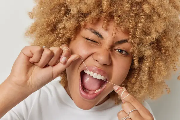 Donna con capelli ricci usa il filo interdentale per una pulizia perfetta.