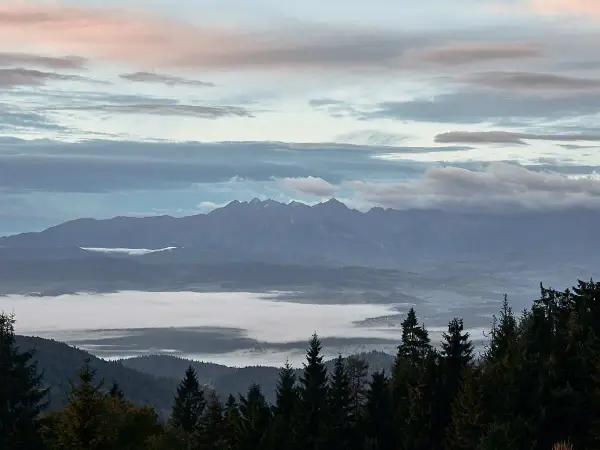 Mglisty poranek na Turbaczu. Wschód słońca maluje niebo pastelowymi barwami nad morzem chmur, a w oddali majaczą Tatry.