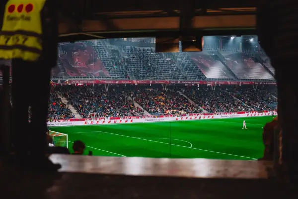 Piłkarz na boisku podczas meczu Wolfsberger – RB Salzburg. Trybuny pełne kibiców, wielkie banery na stadionie.