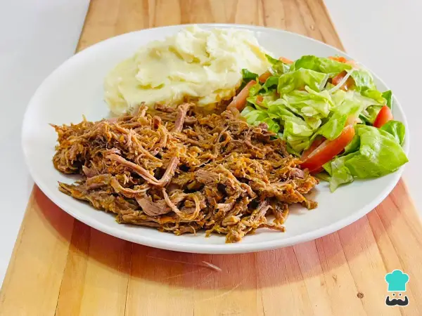 Plato de carne mechada jugosa, puré de papas cremoso y ensalada fresca de lechuga y tomate.