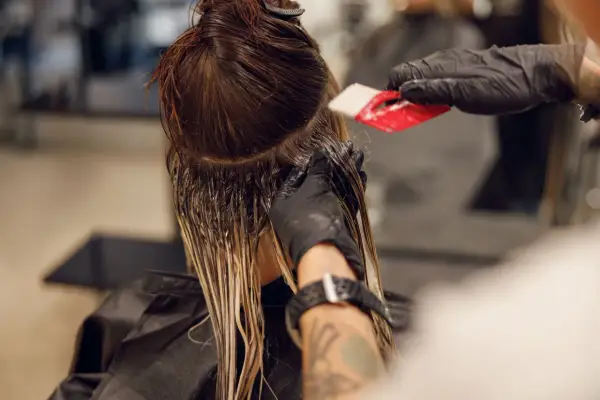 Friseur trägt Farbe auf, um einen sanften Farbverlauf zu erzielen. Die color melting Technik lässt die Töne harmonisch ineinander übergehen.