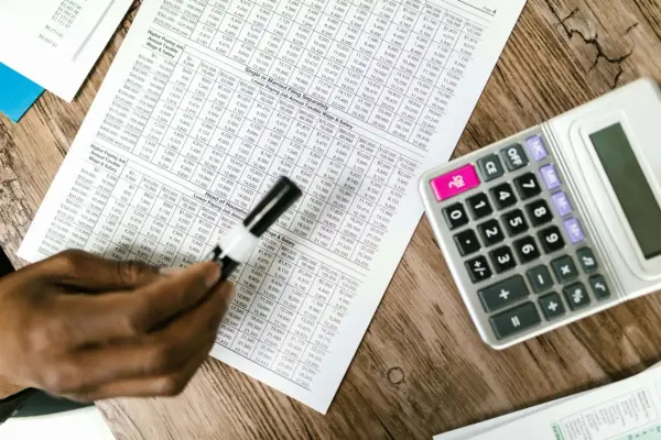 Tabela z danymi finansowymi, kalkulator i ręka analizująca układ rodzajowy kosztów.
