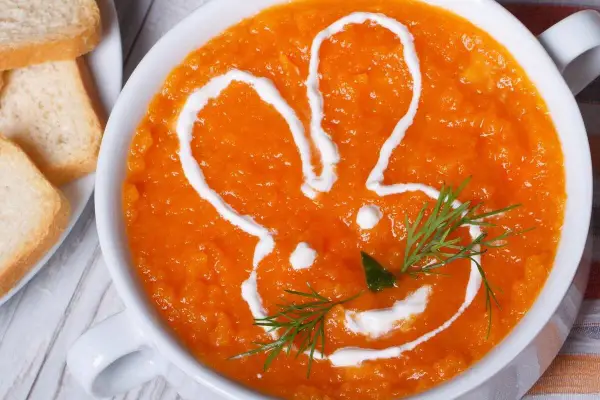 Pomarańczowa marchwianka z ryżem na biegunkę, ozdobiona śmietaną w kształcie królika. Podana z grzankami.