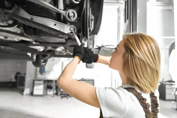 Mechanik sprawdza podwozie auta, szukając objawów uszkodzonego amortyzatora.