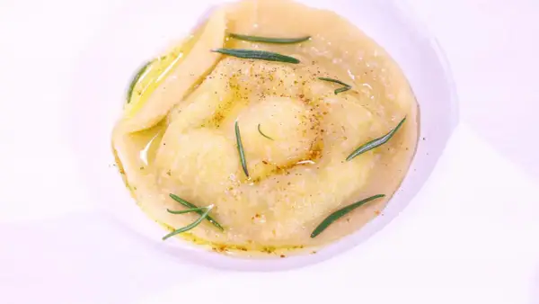 Ravioli z płynnym żółtkiem, ozdobione rozmarynem i przyprawami, danie godne MasterChefa.