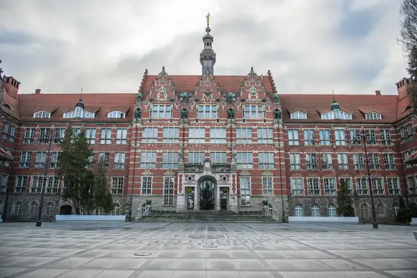 Imponujący budynek Politechniki Gdańskiej, jednej z ważnych uczelni Gdańsk, z charakterystyczną wieżą zegarową i ozdobną fasadą.