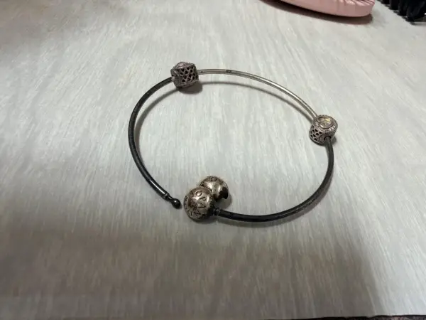 Srebrna bransoletka Pandora z charmsami, która z czasem może żółknąć z powodu reakcji chemicznych.