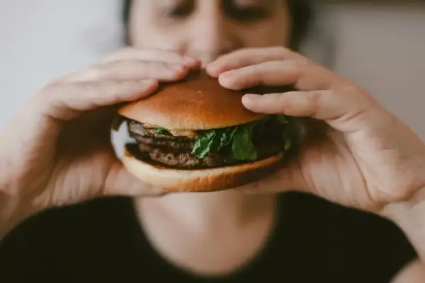 Zbliżenie na ręce trzymające soczystego burgera, idealnego na szybki posiłek. McRoyal makro.