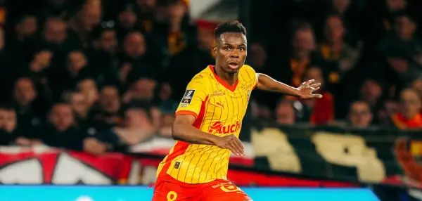 Piłkarz RC Lens w żółto-czerwonej koszulce biegnie po boisku, gotowy do akcji przeciwko Stade Rennais.