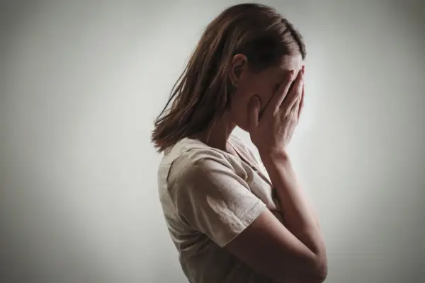 Kobieta zakrywa twarz dłońmi, co może symbolizować różne psychozy objawy, takie jak przytłoczenie czy izolacja.