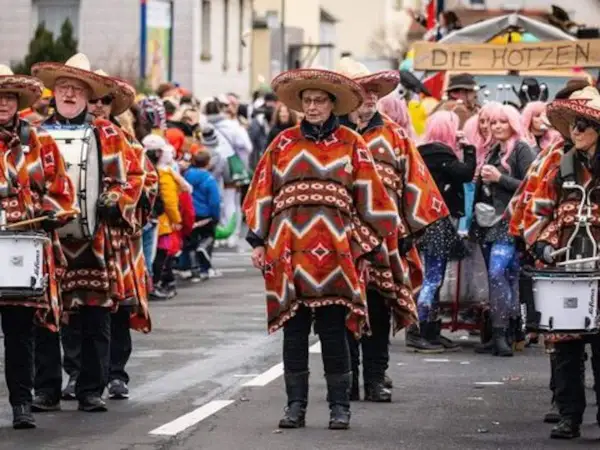 Menschen in bunten Ponchos und Sombreros marschieren mit Trommeln. Sie feiern Fasching, eine Zeit voller Freude und Verkleidungen.