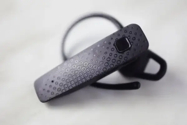 Czarna słuchawka Bluetooth z teksturą kółek. Dowiedz się, jak sparować słuchawki z telefonem.
