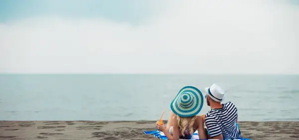 Para relaksu na plaży w Mielnie. Para w kapeluszach popija drinki, ciesząc się widokiem morza. Idealne mielno atrakcje dla dorosłych.