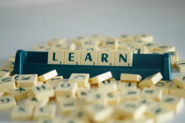 Litery na kafelkach układają się w słowo LEARN, symbolizując naukę i rozwijanie słownictwa. To świetny przykład na word formation C1.