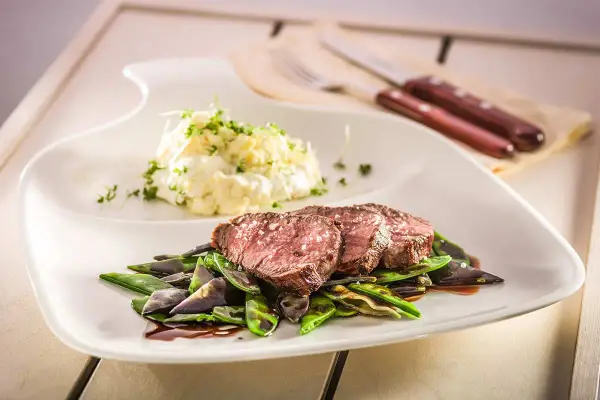 Sternekoch-Qualität: Zartes Kalbsfilet mit knackigen Zuckerschoten und cremigem Kartoffelsalat. Ein Genuss für jeden Gaumen.