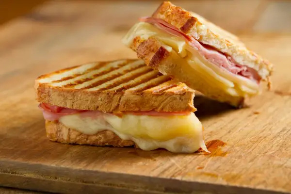Dos deliciosos panini de queso con jamón, el queso derretido se desborda.