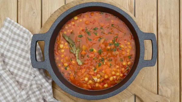 Un plato humeante de garbanzos con verduras, lleno de zanahoria, cebolla y especias, listo para ser disfrutado.