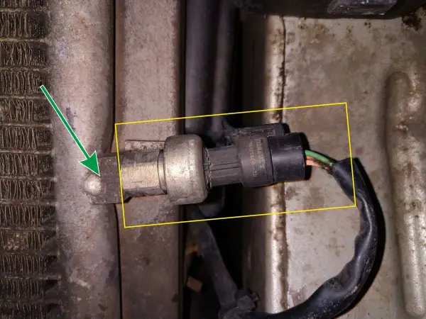 Czujnik temperatury w Renault Kangoo znajduje się przy chłodnicy klimatyzacji. Strzałka wskazuje jego lokalizację.
