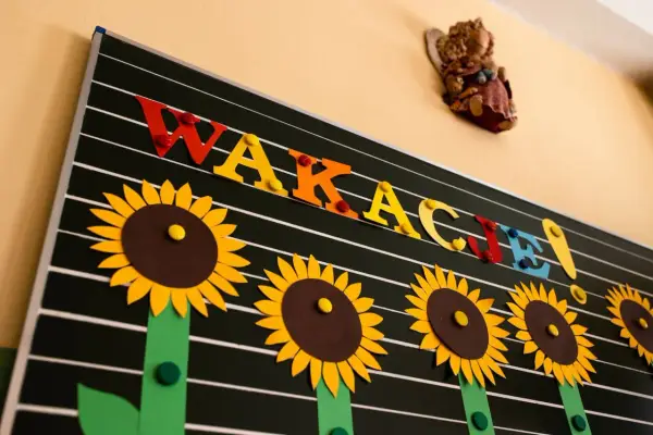 Tablica z napisem "WAKACJE!" ozdobiona słonecznikami.