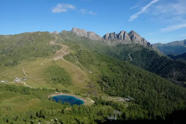 Panorami alpini con sentieri per passeggiate facili vicino a Trento, un lago azzurro e cime rocciose.