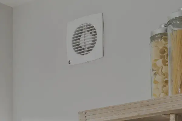 Aspiratore centrifugo o elicoidale bianco montato su parete grigia, accanto a barattoli di pasta.