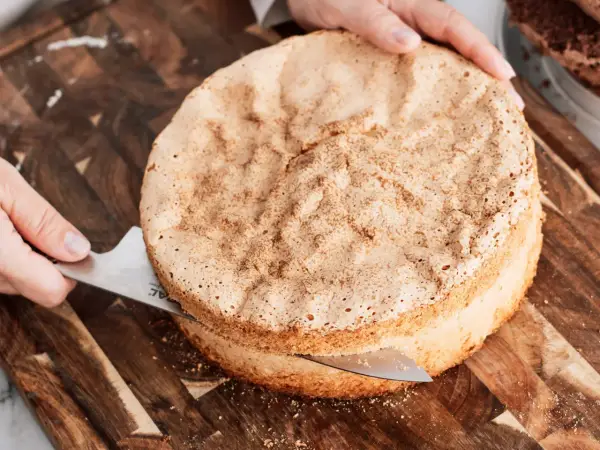 En person skär en fluffig sockerkaksbotten med en kniv. Perfekt för ditt nästa cake recept!