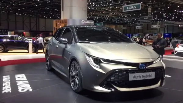 Elegancki, srebrny Auris Hybrid prezentowany na targach motoryzacyjnych. Na podłodze widoczny napis "NEW AURIS WORLD PREMIERE".