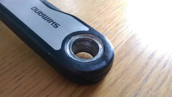 Close-up of a Shimano crank arm showing the threaded hole for pedal installation. This detail is crucial for understanding the correct mtb pedal thread size.