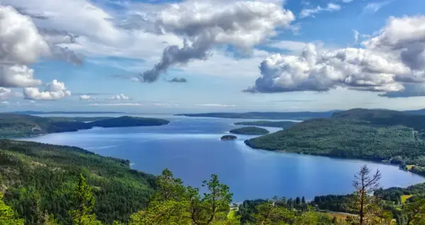 Vacker utsikt över en sjö med öar, omgiven av skogklädda berg. Ett perfekt ställe att uppleva Stockholms naturreservat.